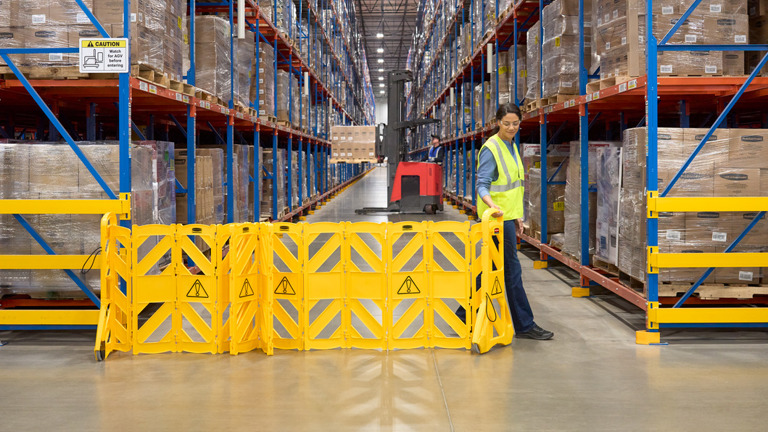 Female Warehouse Staff holding a 4m Mobile Barrier