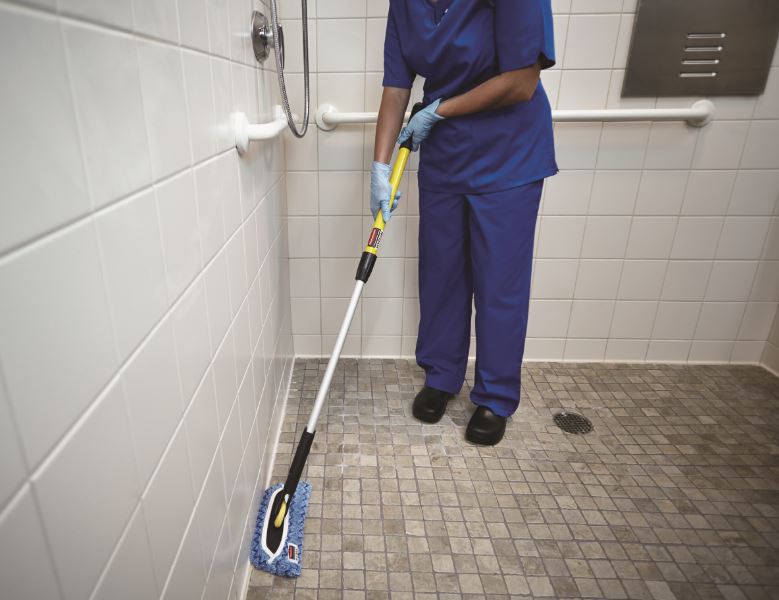 A Person cleaning an area on the Bathroom using HYGEN™ PUlSE™ Microfibre Mop Kit