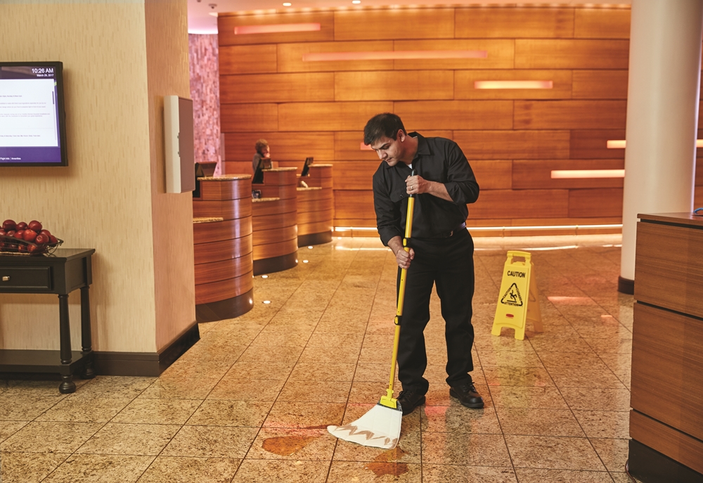 A cleaner sweeping a hotel floor lobby using HYGEN™ PUlSE™ Microfibre Mop Kit