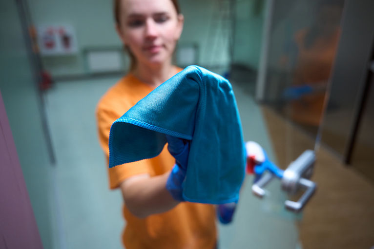 Woman Cleaning Glass Door with Washable Cloth and Spray