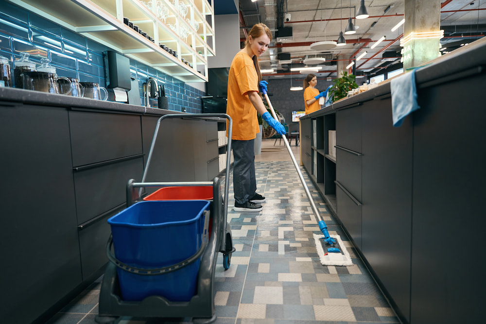 A staff member using a Rubbermaid flat mop system.