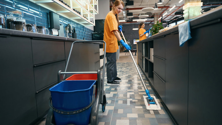 A staff member using a Rubbermaid flat mop system.