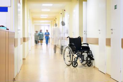 A clean hospital corridor with a wheelchair and a few members of staff